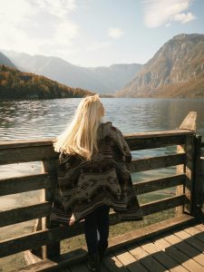 Woman looking over a calm mountain lake, symbolizing reflection, nervous system healing, and the journey of trauma-informed therapy in Coquitlam.