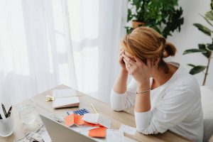 Woman showing signs of stress and burnout while working at her desk.